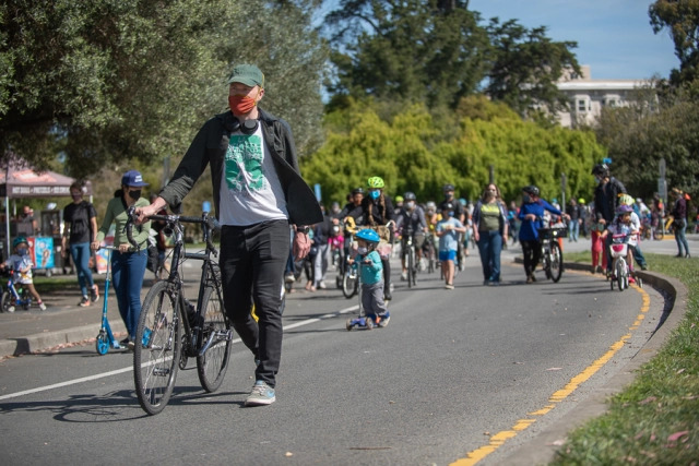 Parents and children ride bikes, walk, and scoot, on a car-free road in Golden Gate Park.